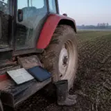 O imagine de aproape cu partea laterală a unui tractor roșu parcat pe un câmp arat